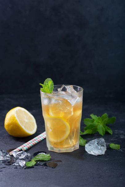 Lemon ice tea on dark background with mint and ice, nice drink for summer hot season - Foto, afbeelding