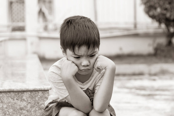 Tono seppia. Bambino di 6 anni. Solo asiatico bambino sentire triste, mal di testa e stressato. Si sentiva solo al parco giochi. Ragazzo infelice. Umore ed emozioni. - Foto, immagini
