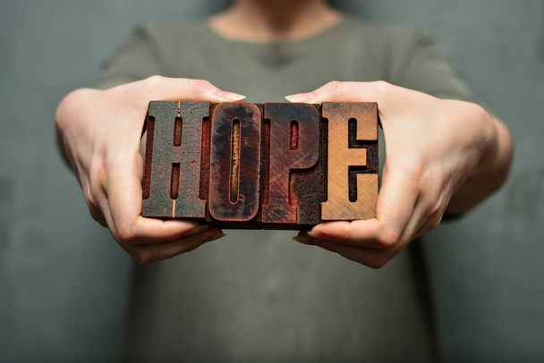 Donna con la parola "speranza" fatta di lettere tipografiche in legno. - Foto, immagini