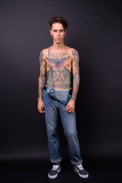 Studio shot of young handsome rebellious man shirtless against black background - Foto, Imagem