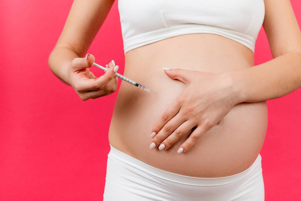 Lähikuva, että raskaana oleva nainen pistää insuliinia mahaansa värikkäällä pohjalla ja kopioi sitä. Sokeri valvonta raskauden aikana käsite. - Valokuva, kuva