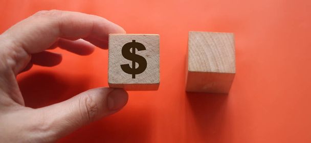 Wooden block with the US Dollar symbol in hand holding it and another empty one. Red background. Profit choise business concept. - Photo, image