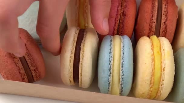 teen girl takes macaron from box and bites him. - Video