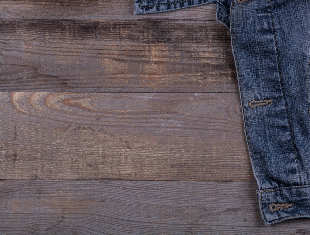 Дуже стара синя джинсова куртка на дерев'яному столі
 - Фото, зображення