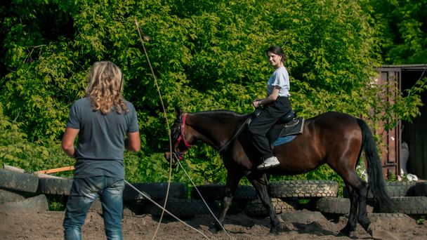 Nuori nainen sinisessä paidassa oppii ratsastamaan hevosella - Valokuva, kuva