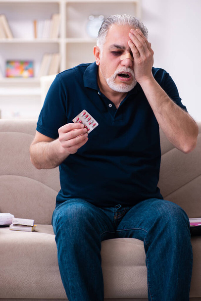 Old injured man in budget planning concept - Photo, image