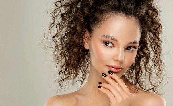 Beautiful brunette girl with curly hair gathered in a ponytail.Cosmetics, makeup and beauty. Wavy Hairstyle - Photo, Image