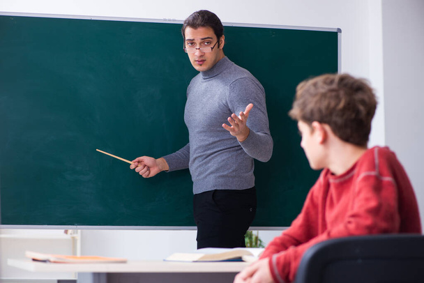 Young male teacher and schoolboy in the classroom - Foto, Imagen