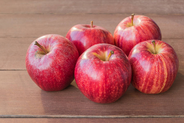 pięć czerwonych jabłek na drewnianym stole widok z bliska - Zdjęcie, obraz
