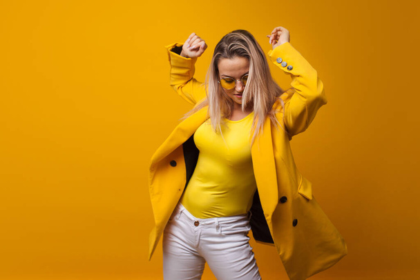 Stylish bright young woman dancing and rejoicing. The girl in the yellow jacket - Photo, Image