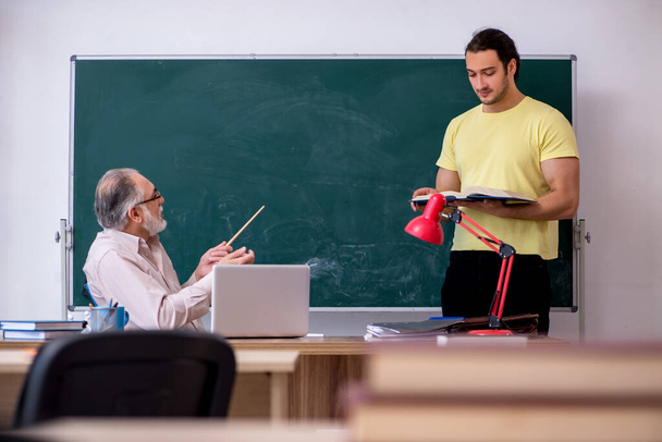 Old teacher and young male student in the classroom - Photo, Image