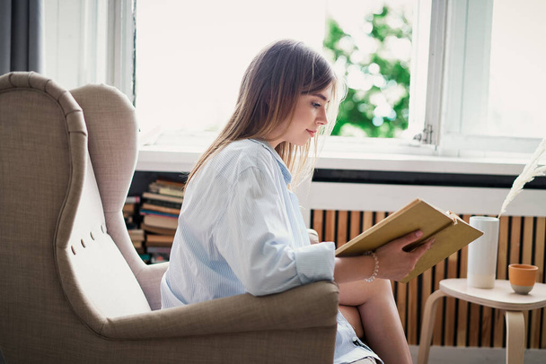 Beautiful girl reading a book at home. Leisure indoors entertainment - Fotó, kép