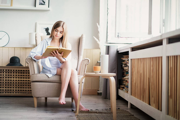 Beautiful girl reading a book at home. Leisure indoors entertainment - Foto, afbeelding