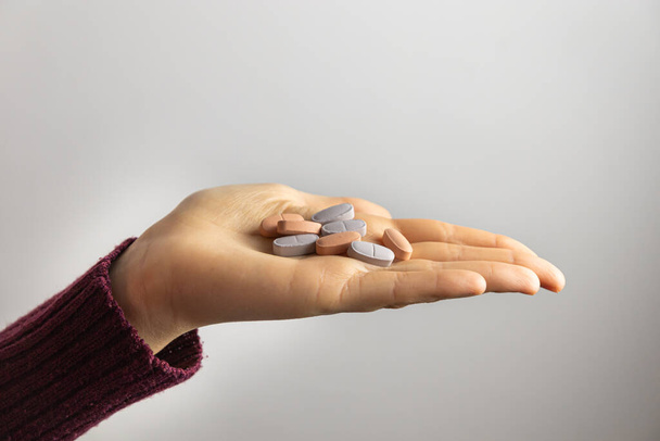 Gros plan de la main d'une femme tenant des pilules. Image horizontale avec fond blanc. - Photo, image