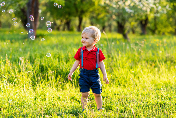 gyermek fiú szórakoztató játszani a természetben fényes szappanbuborékok - Fotó, kép