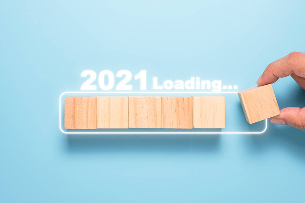 Рука кладет деревянные кубики к белому блоку для отсчета и загрузки до 2021 года. С новым годом, чтобы начать новый проект и бизнес-концепцию. - Фото, изображение