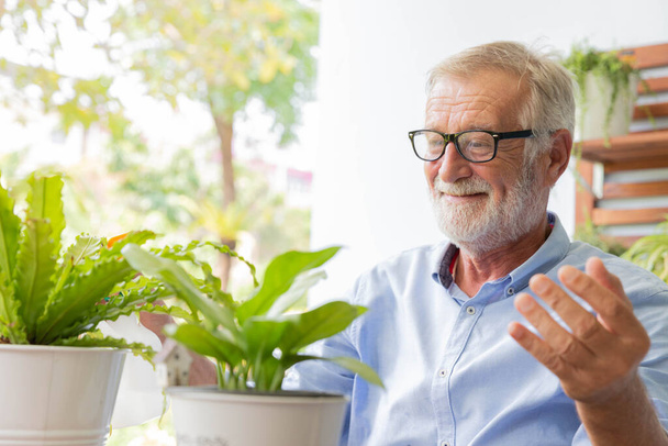 Senior retirement man is watering his small plant while relax at home - Foto, imagen