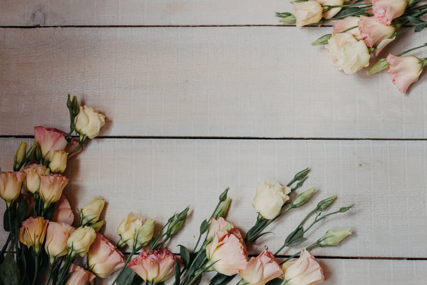 招待状やポストカードのための美術品のスタイルで白とピンクのイースタスで作られた花のフレーム。白い木の板の背景にある絵花で、パステルカラーの文字やコピーのためのスペースがあります。. - 写真・画像
