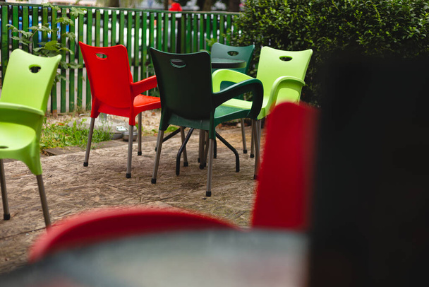 Pusty stół i krzesła na tarasie kawiarni w pochmurny i deszczowy dzień. Bardzo żywe kolory i kolorowe na zewnątrz.  - Zdjęcie, obraz