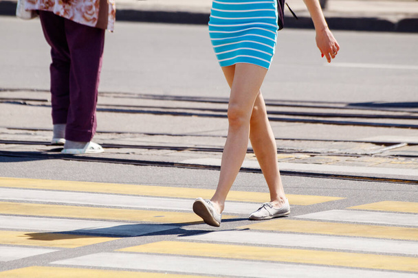 jonge vrouw steekt de weg over bij een voetgangersoversteek op zonnige zomerdag - Foto, afbeelding
