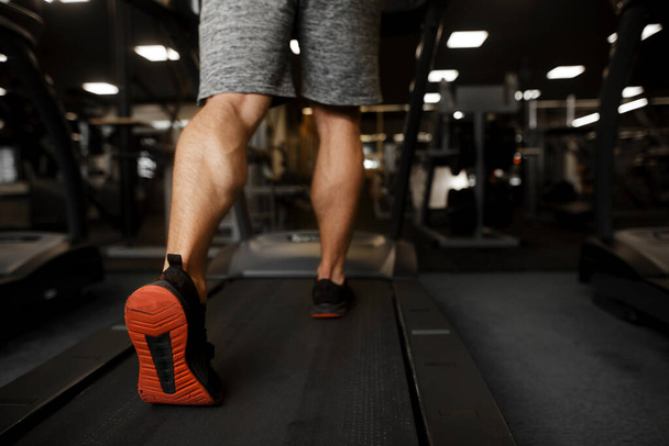 Fitness man running on treadmill. Strong man with muscular legs in gym - Фото, зображення