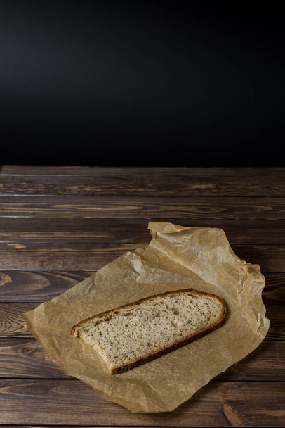  rebanada recién horneada de pan rebanado en papel de regalo. mesa de madera, papel de hornear, pan de panadería. - Foto, imagen