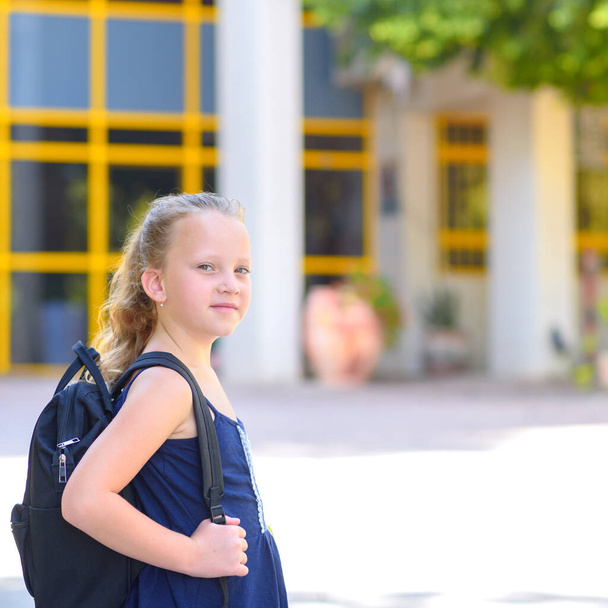 Портрет счастливого улыбающегося ребенка, возвращающегося в школу. Маленькая веснушка с сумкой ходит в начальную школу. Ребенок начальной школы. Ученик идет учиться с рюкзаком. - Фото, изображение