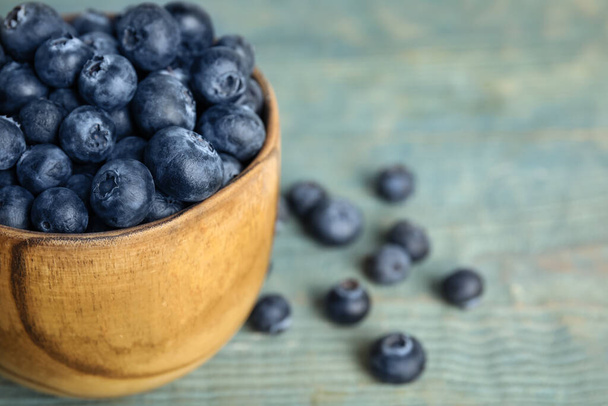 Fresh ripe blueberries in bowl on wooden table, closeup. Space for text - Foto, Imagen