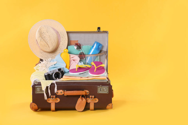 Valise vintage emballée avec différents objets de plage sur fond orange, espace pour le texte. Vacances d'été - Photo, image