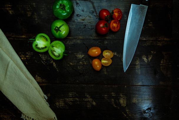 still life with fresh red, green and yellow tomatoes freshly picked from the garden on the wooden table and kitchen knife - Photo, Image