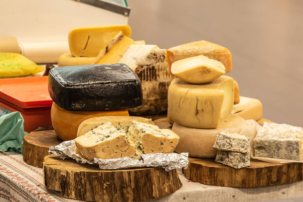 Kulinaarinen buffet, jossa on erityyppisten juustojen esittely, jotka esitetään puulevyillä. Keittiö ulkona. Katunäyttelyosasto. - Valokuva, kuva