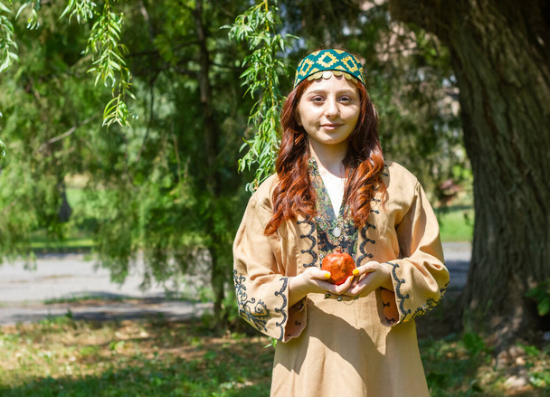 Arménská mladá žena v tradičním oblečení v lese s granátovým jablkem - Fotografie, Obrázek