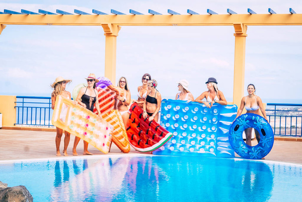Happy young women have fun together enjoying the leisure at the pool during summer holiday vacation - trendy lilos and blue water with cheerful people in friendship - Photo, Image