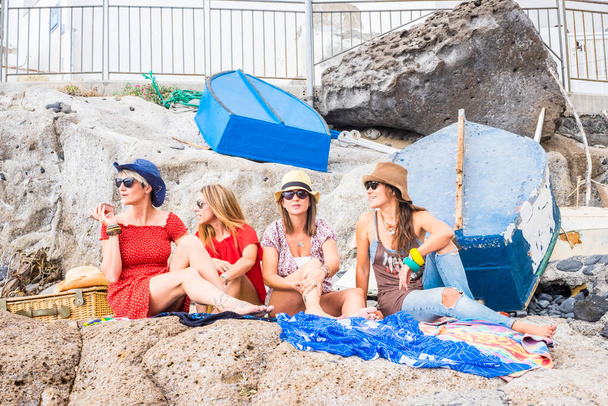 kadın grup arkadaşları kayaların üzerinde oturan yakın: deniz ve açık hava etkinliği dostluk rahatlatıcı tatil ve eğlence keyfini çıkarın. mutlu yaşam tarzı insanların, dört kadın yaz güneşi altında beraber - Fotoğraf, Görsel