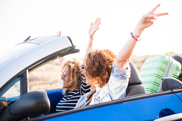 Paar von Freunden erwachsene Frauen, die zusammen frei und unabhängig auf dem Auto mit Bergen und wilder Naturwüste im Hintergrund reisen - Foto, Bild