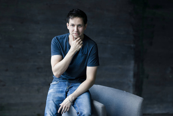Portrait of handsome man in blue shirt and jeans. Portrait of a sexy man sitting on the chair and thinking. Portrait of sexy man - Фото, изображение