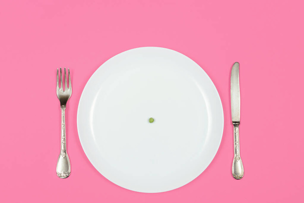 Dieta, anoreksja i koncepcja kryzysu żywnościowego. jeden groszek na pustej białej tabliczce - Zdjęcie, obraz