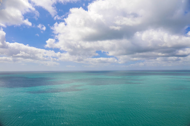Uitzicht op de oceaan met turkoois water en blauwe lucht met wolken - Foto, afbeelding