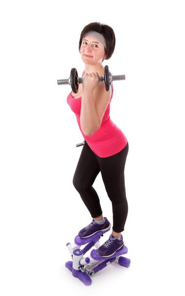 The girl is engaged in fitness with dumbbells on stepper. On a white background. - Foto, imagen