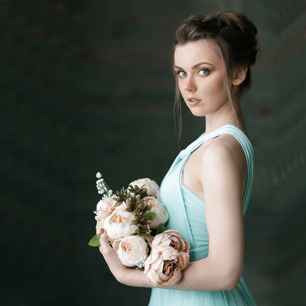 Κοντινό πλάνο πορτρέτο της γυναίκας μοντέλο στο φόρεμα και όμορφο χτένισμα κρατώντας λουλούδια. Αισθησιακή κυρία με λουλούδια. - Φωτογραφία, εικόνα