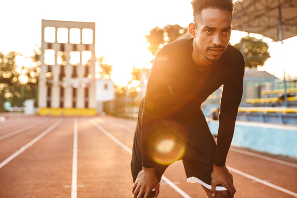 Image of tense african american man standing at running track on sports ground outdoors - Φωτογραφία, εικόνα