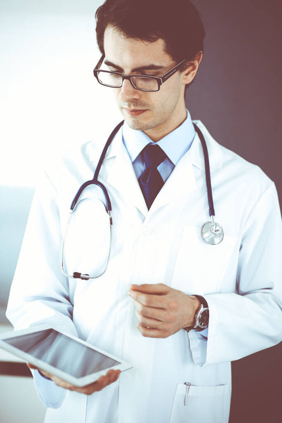 Doctor man using tablet computer for network research or virtual disease treatment. Perfect medical service in clinic. Modern medicine, medic data and healthcare concepts - 写真・画像