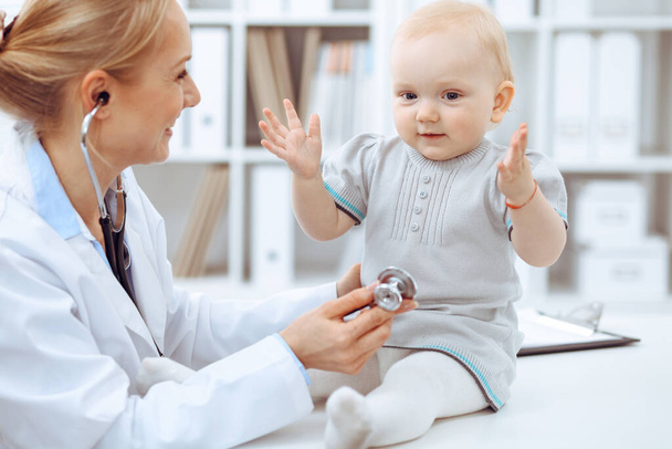 Doctor and patient in hospital. Little girl is being examined by doctor with stethoscope. Medicine concept - Photo, image