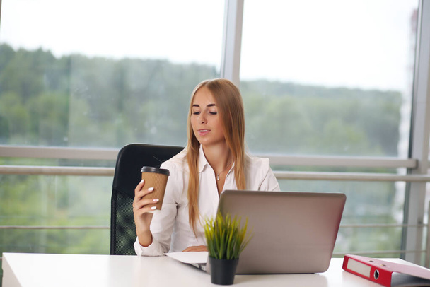 manager in the office, sitting blonde in a white shirt - Fotoğraf, Görsel