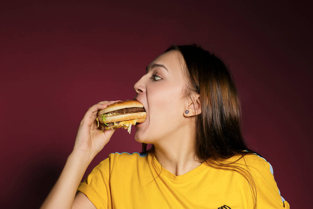 Hermosa joven mujer comiendo hamburguesa
 - Foto, Imagen