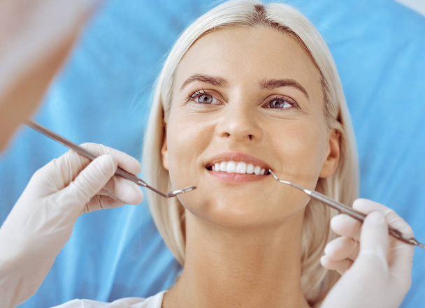 Smiling blonde woman examined by dentist at dental clinic. Healthy teeth and medicine concept - Foto, Bild
