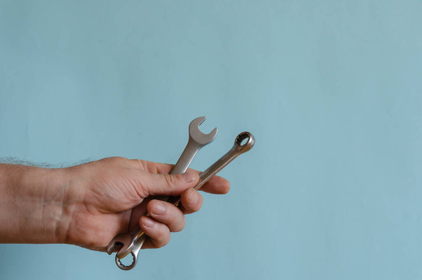 Két kulcs egy férfi kézben. Egy férfi keze egy krómozott csavarkulcsot és egy átokkulcsot tart. Középkorú férfi az európai fajból. Kézi szerszám. - Fotó, kép