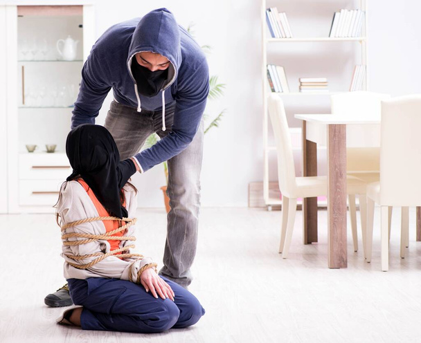Aseistettu mies pahoinpitelee nuorta naista kotona - Valokuva, kuva