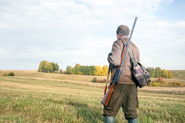 Хантер с рюкзаком и охотничьим пистолетом. Человек охотник на открытом воздухе в осенней охоте. - Фото, изображение