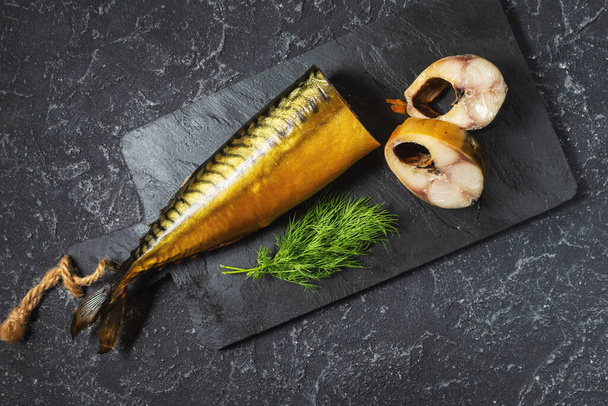 plátky uzené rybí makrely nebo škeble na černém kamenném stole. Horní pohled - Fotografie, Obrázek